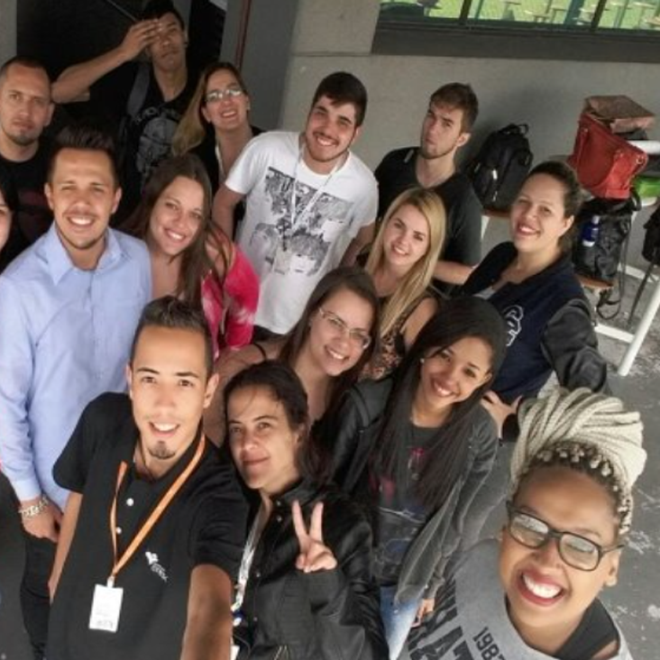 Grupo de pessoas sorrindo e posando para uma selfie em um ambiente descontraído em atividade do Programa de Qualificação Almaviva do Brasil.