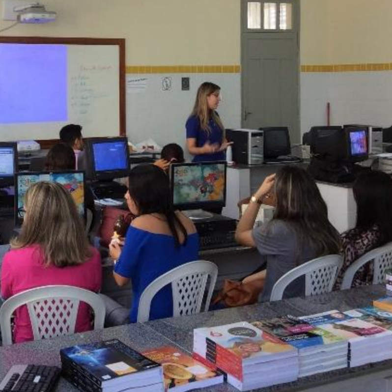 Grupo de pessoas sentadas em mesas, utilizando computadores durante atividade do projeto Educonexão